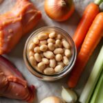 Raw ingredients for a classic ham hock and beans recipe including navy beans and vegetables.
